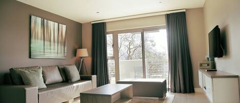 A modern living room with a sofa, coffee table, and a flat-screen TV.