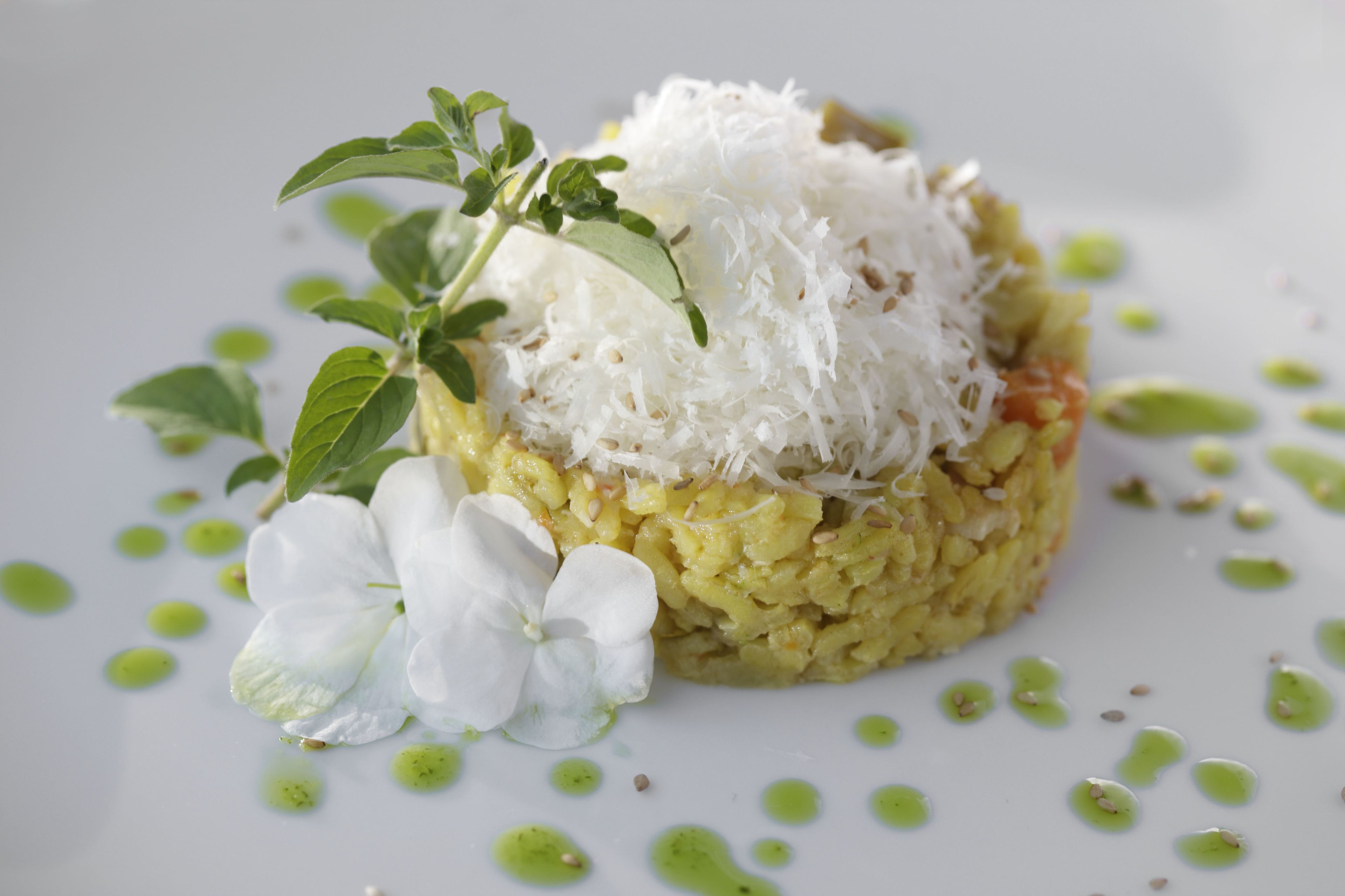 A dish with shredded coconut, a flower, and green dots on a white plate.