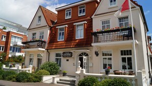 A two-story hotel with a red-tiled roof, balconies with black railings, and flower boxes. - Hotel Villa Undine (Groemitz)