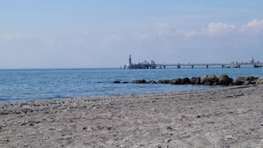 A beach with a pier extending into the water, featuring a lighthouse and several structures. - Hotel Villa Undine (Groemitz)