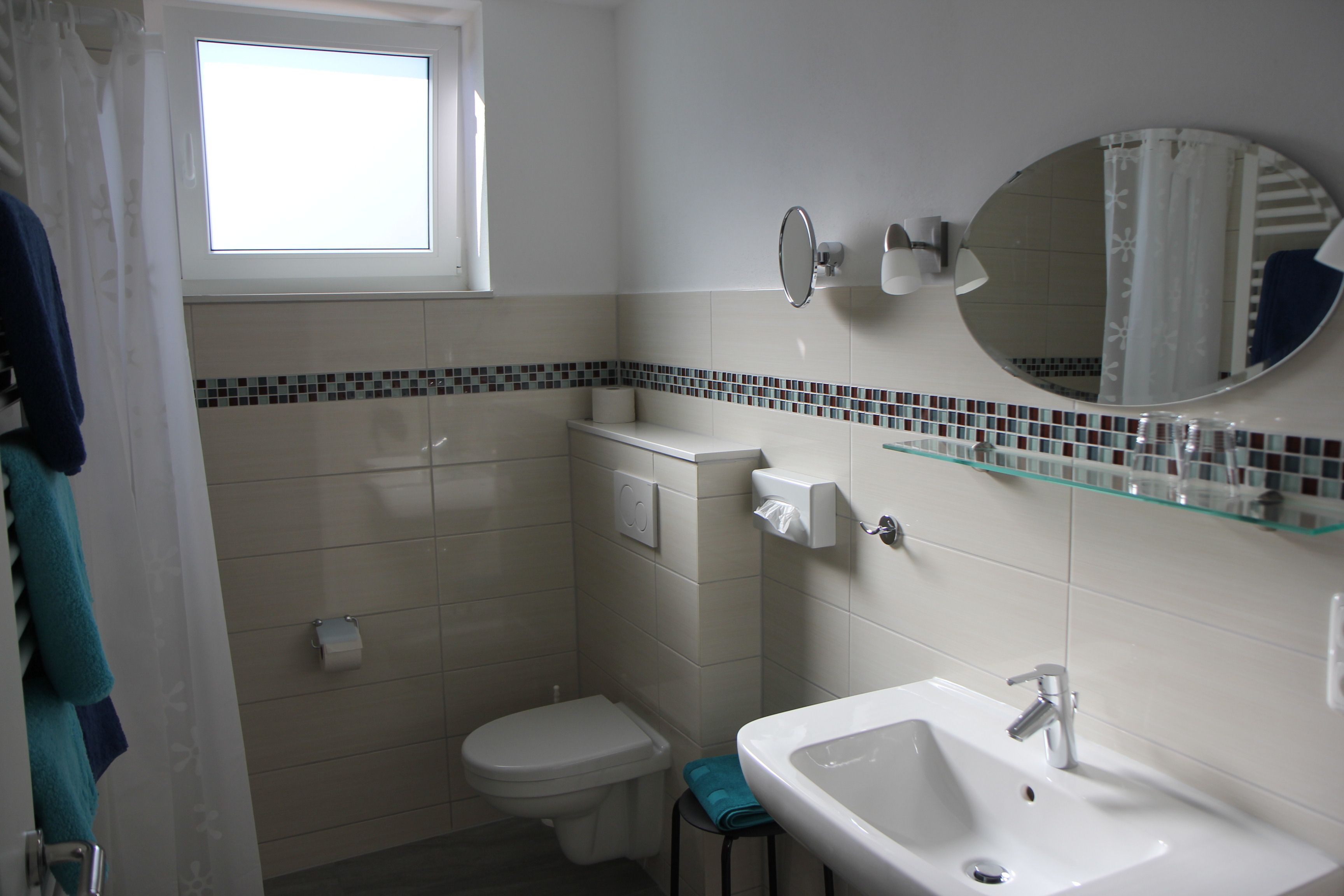 Ein Badezimmer mit Toilette, Waschbecken und einem Fenster.