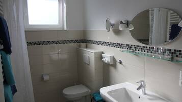 Ein Badezimmer mit Toilette, Waschbecken und einem Fenster.