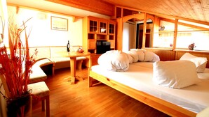 Ein gemütliches Holzhaus-Interieur mit einem Bett, einem Esstisch und einer Küchenzeile.