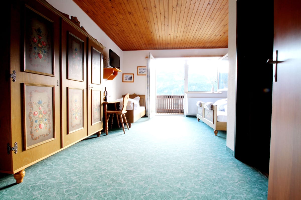 A hotel room with a wooden ceiling, a dining area with a table and chairs, a bed, and a view of the outdoors.