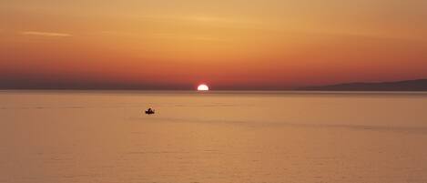 Mar tranquila al atardecer con un barco a lo lejos.