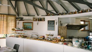 A buffet area with a variety of food items and a selection of wine bottles on shelves. - Blue Bay (Cefalù)