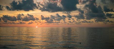 A sunset over a calm sea with clouds in the sky.