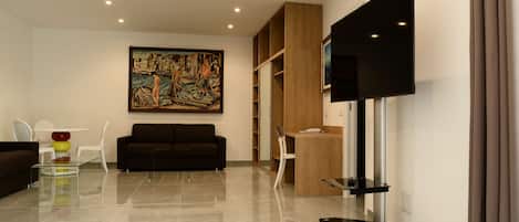 A modern living room with a flat-screen TV, a painting, a sofa, a coffee table, and a bookshelf.