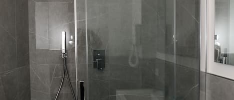 A modern bathroom with a glass-enclosed shower, a white sink, and a large mirror.