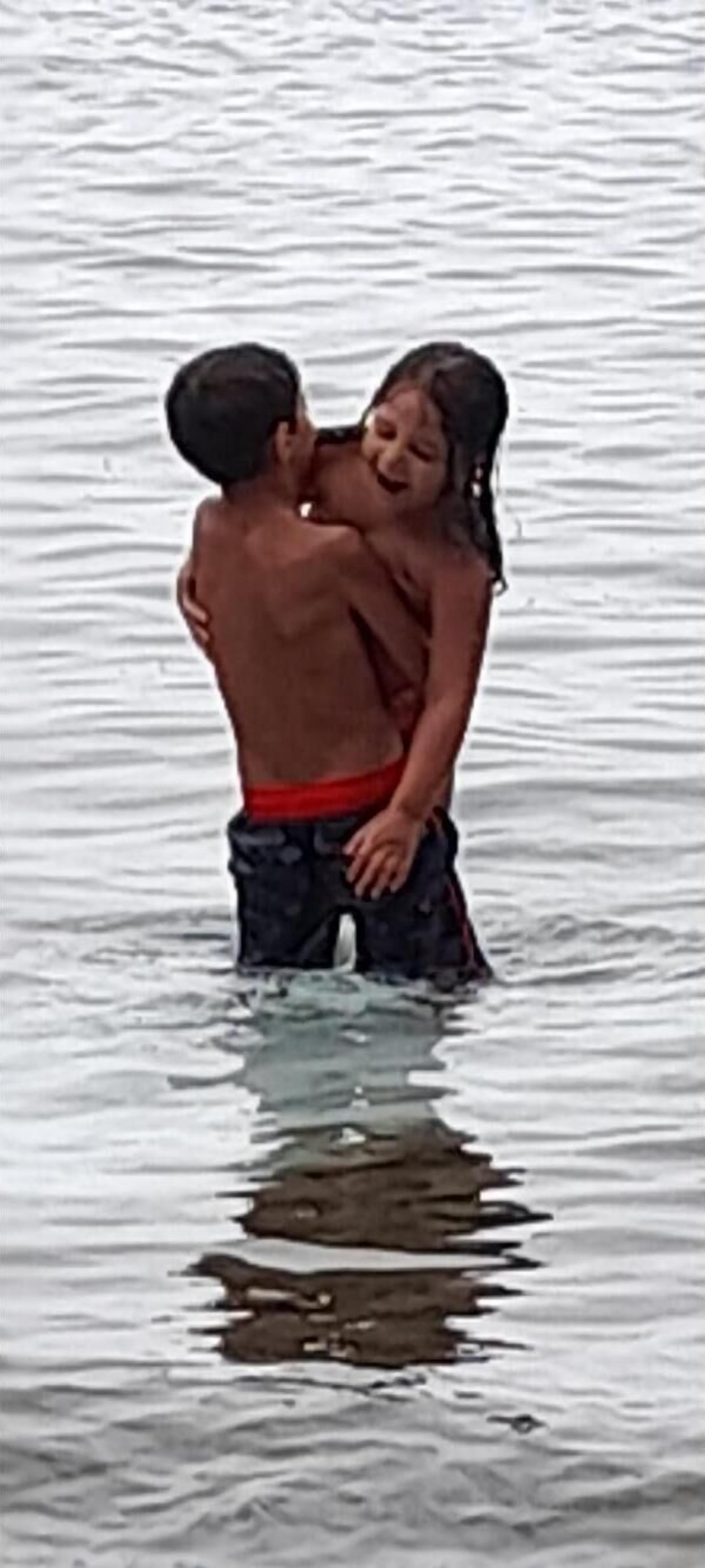 Two people embracing in shallow water.