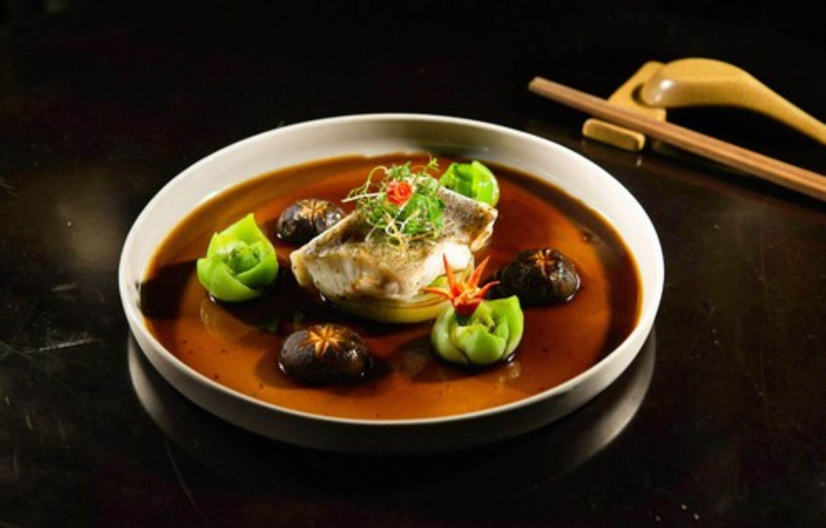 Eine Schüssel mit Fisch und Knödeln, dazu Essstäbchen.