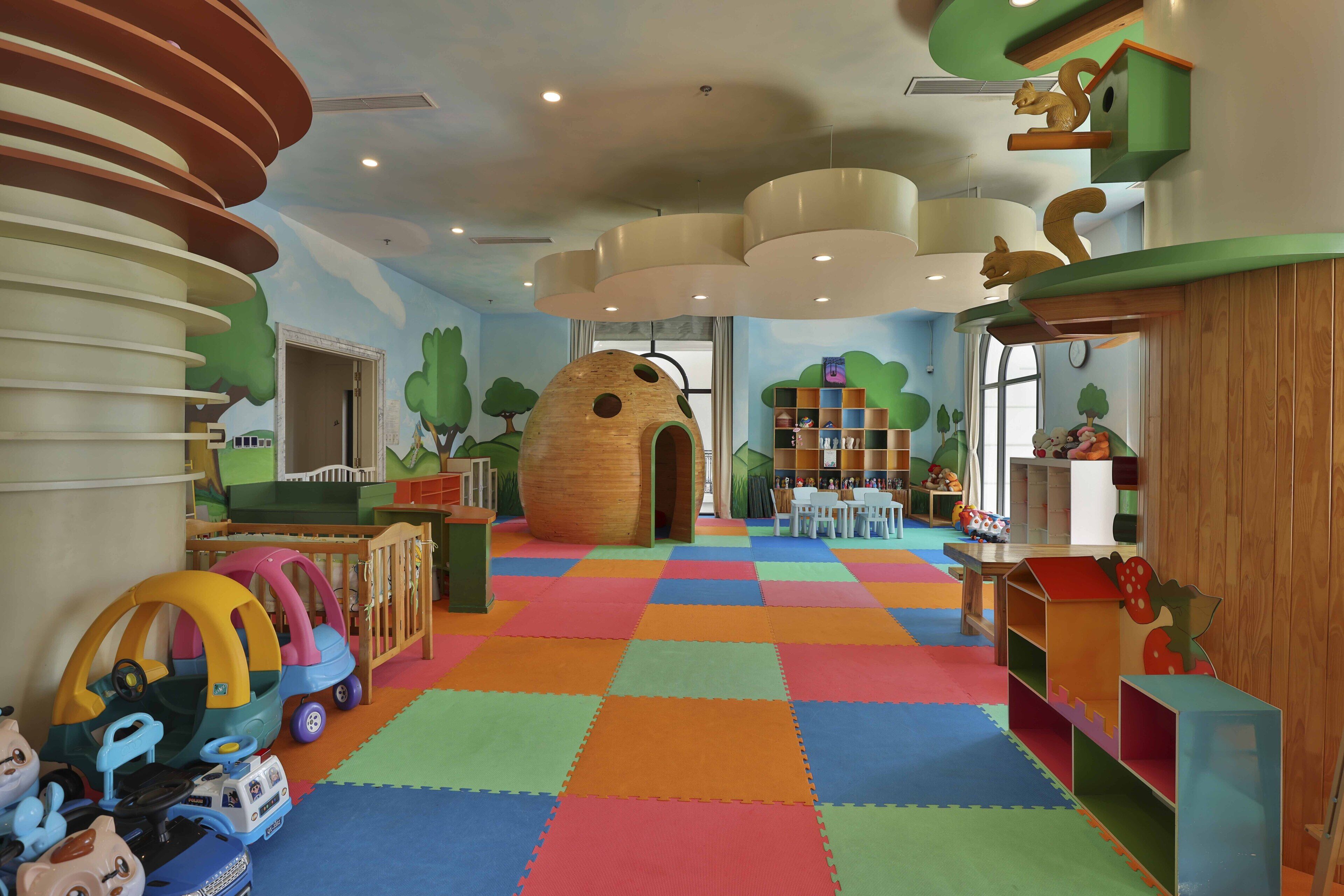 A children's play area with colorful mats, play structures, and a large wooden playhouse.