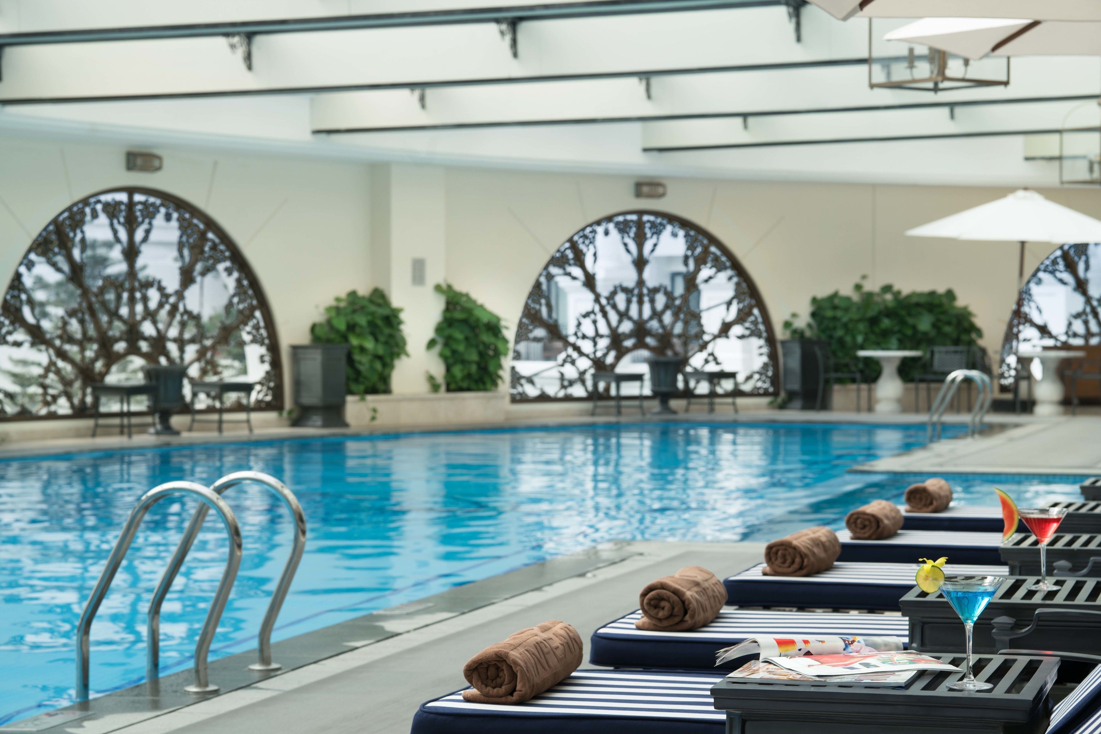 Zona junto a la piscina con sillones de playa, toallas y sombrillas.