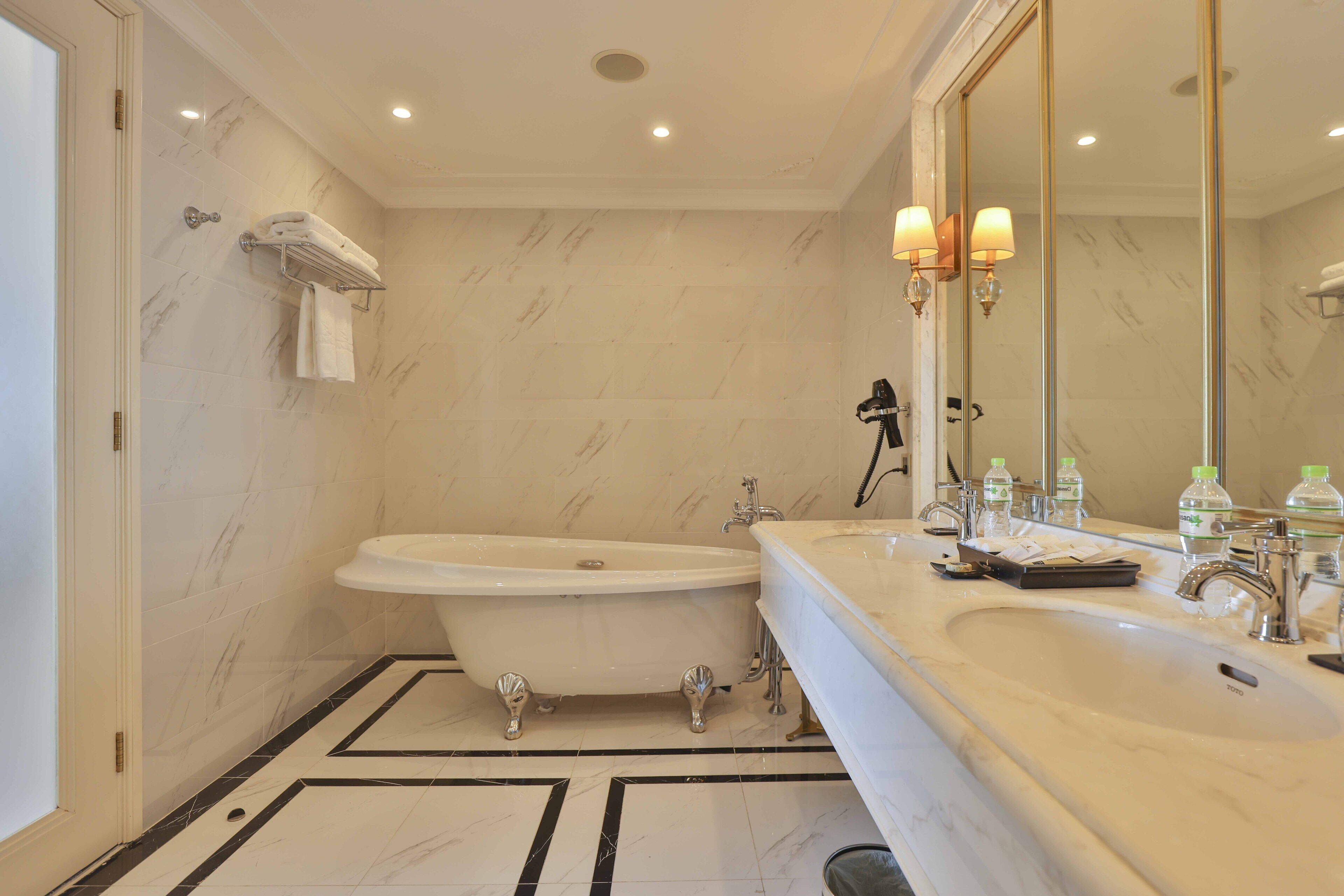 A bathroom with a freestanding bathtub, a large mirror, and a vanity with a sink.
