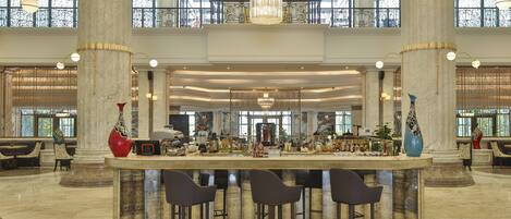 A spacious lobby with a central bar area, high ceilings, and large columns.