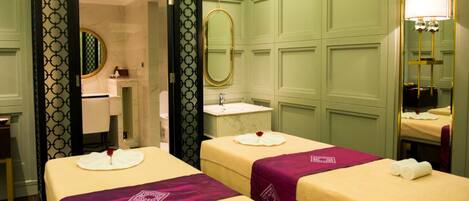Habitación de hotel con tres camas, un baño y un espejo.