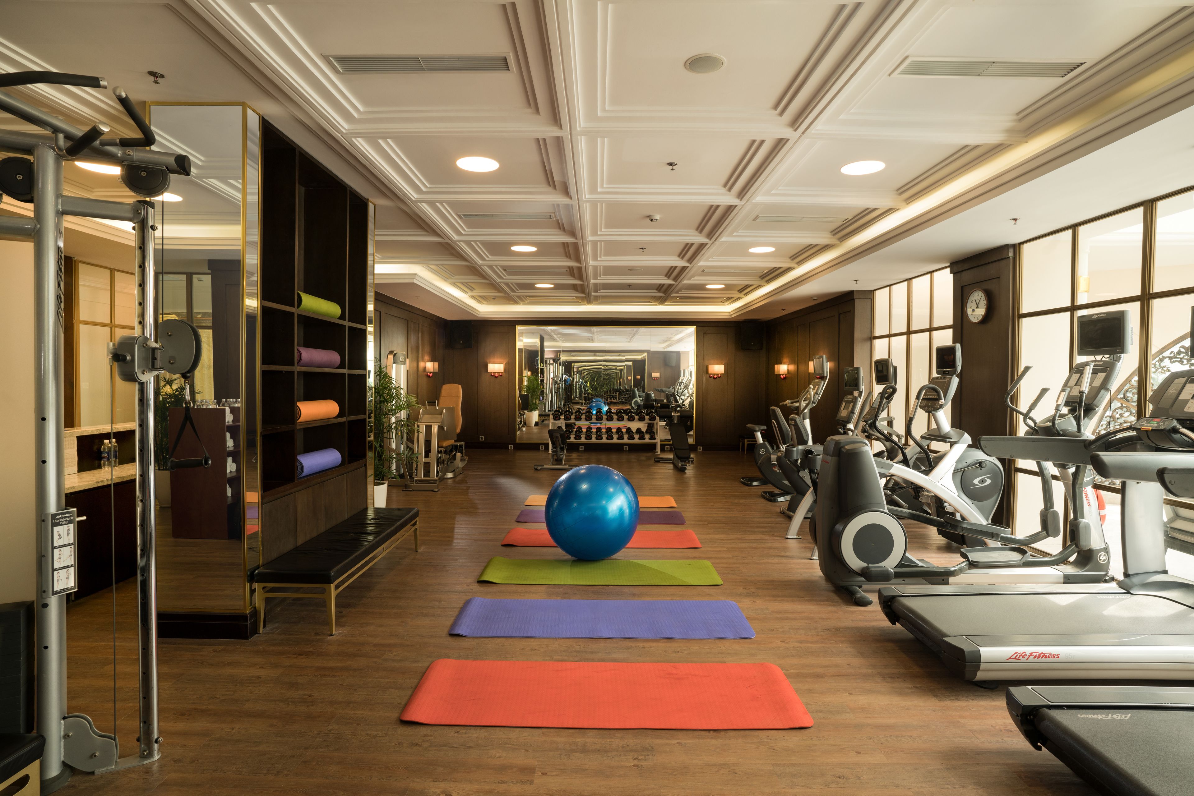 Una palestra con attrezzature per esercizi, tappetini da yoga e una grande palla blu per allenamento.