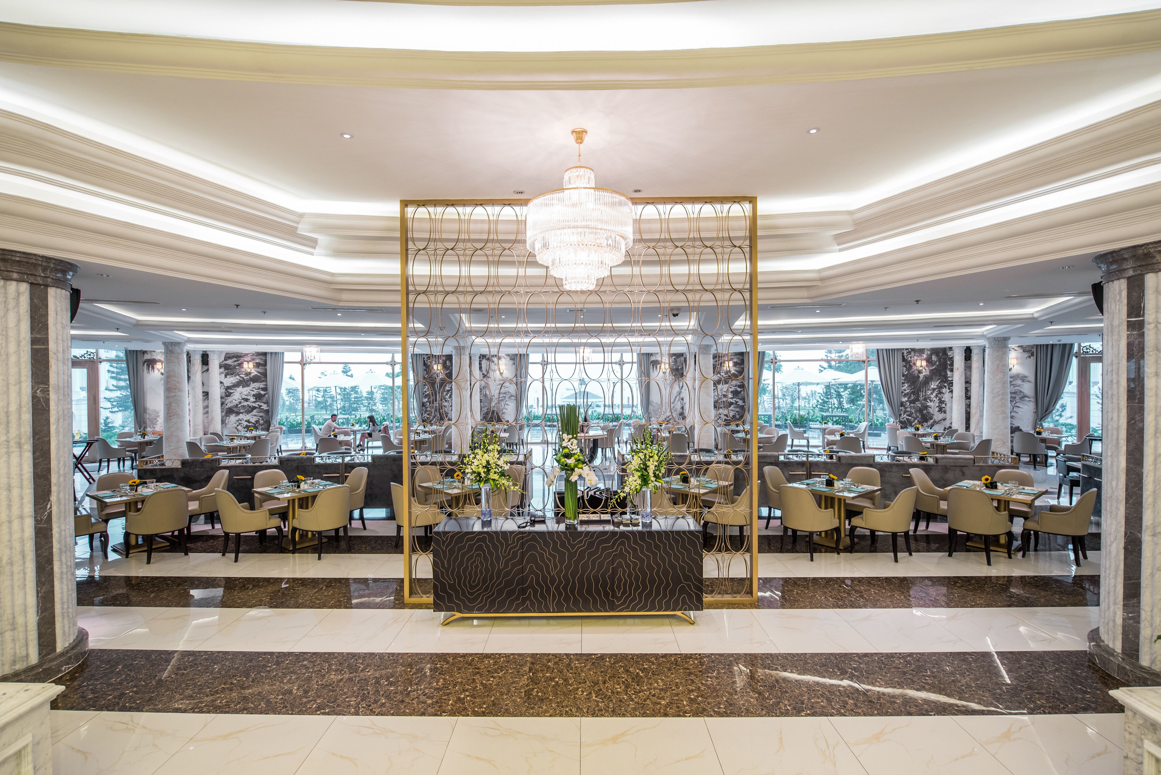 A spacious lobby with a central reception desk, multiple seating areas, and large windows offering a view of the cityscape.