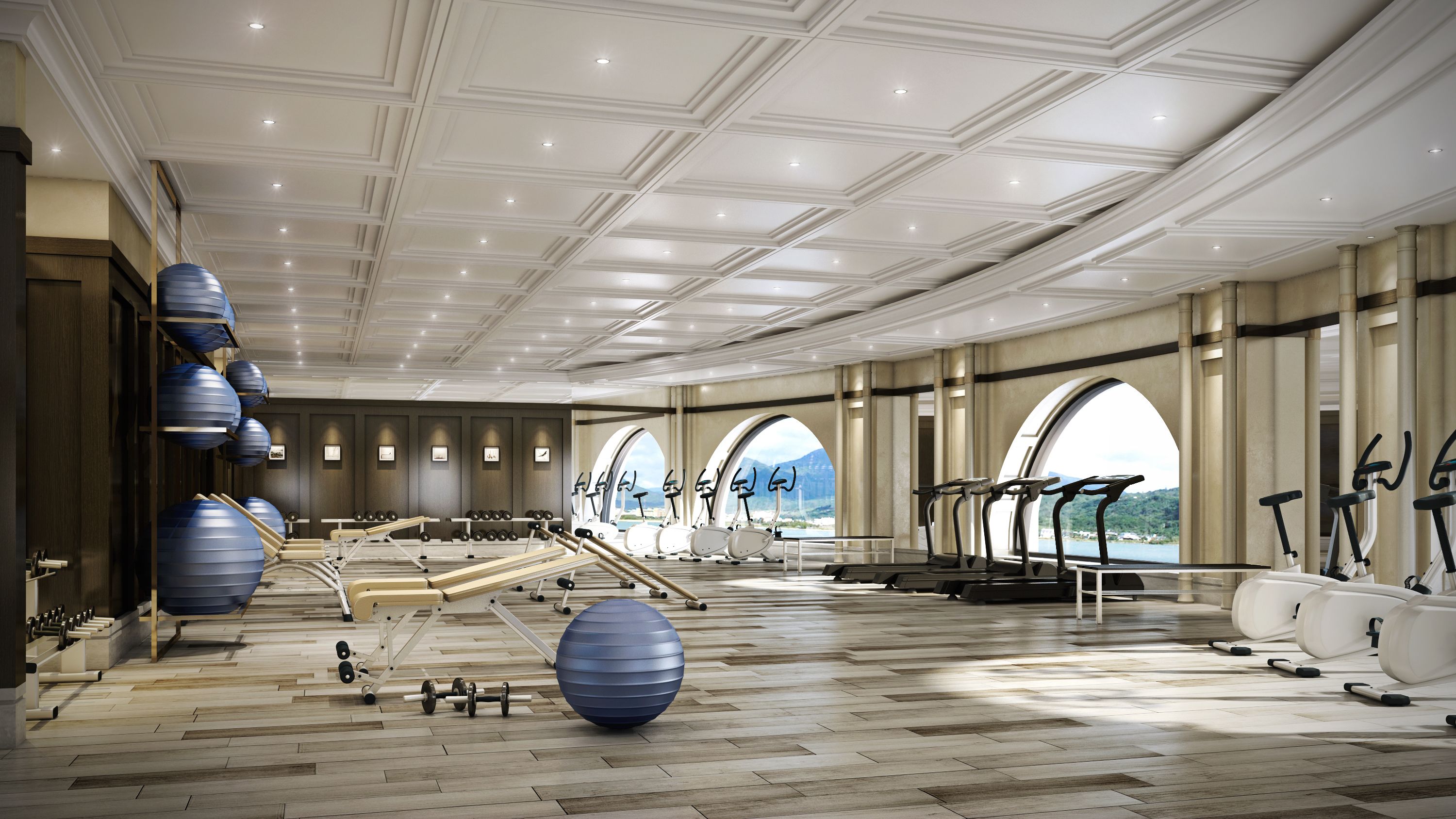 A spacious gym with exercise equipment, wooden flooring, and large windows offering scenic views.