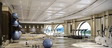 A spacious gym with exercise equipment, wooden flooring, and large windows offering scenic views.