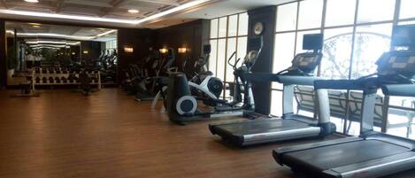 Un gimnasio con cintas de correr, elípticas y pesas sueltas.