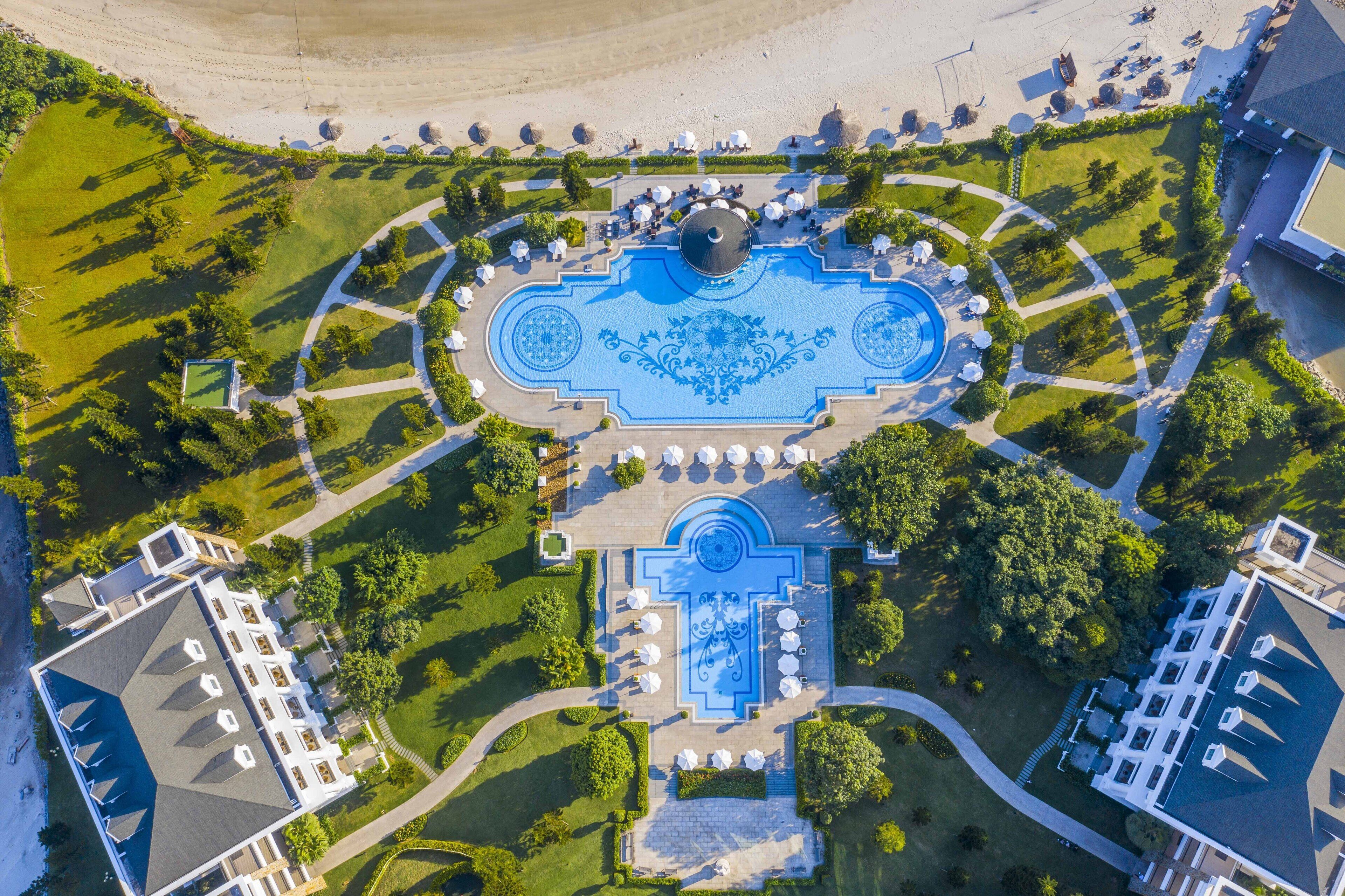 An aerial view of a hotel with a central courtyard, outdoor seating, and a pool.
