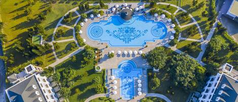 An aerial view of a hotel with a central courtyard, outdoor seating, and a pool.