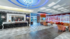 A modern lobby with a reception desk, seating area, and large windows. - Hatipoglu Beach Hotel (Alanya)