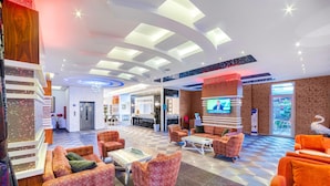 A spacious lobby with a checkered floor, multiple seating areas, a television, and a large window. - Hatipoglu Beach Hotel (Alanya)