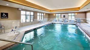 Une piscine intérieure à l’eau claire, équipée d’un dispositif d’élévation pour faciliter l’accès et de chaises longues.