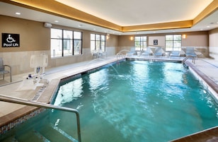 Una piscina interior con agua cristalina, un elevador de piscina y sillones de descanso.