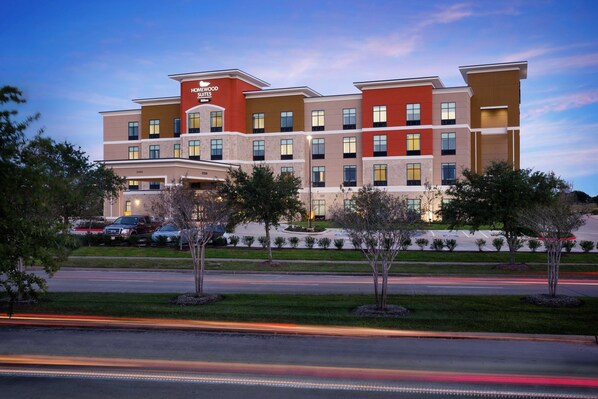 A multi-story hotel with a modern architectural design, featuring a prominent entrance and a landscaped front yard.