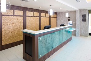 Un mostrador de recepción de diseño moderno, con un panel de vidrio y otro de madera con un patrón texturizado.