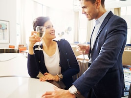 Una pareja sentada a una mesa en un ambiente interior luminoso, posiblemente un hotel o restaurante, con muebles modernos y un ambiente relajado.