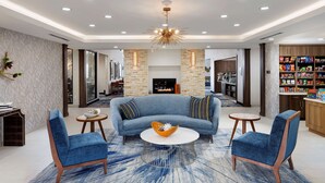 Un salon moderne avec un canapé bleu, deux fauteuils, une table basse et une cheminée.