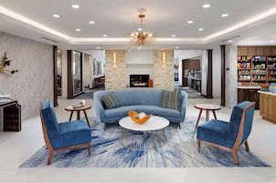Una sala de estar moderna con un sofá azul, dos sillones, una mesa de centro y una chimenea.