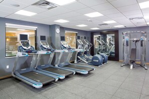 Un gimnasio con cintas de correr, elípticas y equipo de pesas.