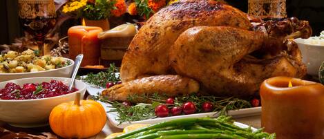 Un pavo asado rodeado de guarniciones y adornos varios.
