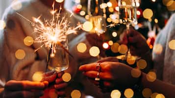 Hands holding glasses with sparklers, suggesting a festive or celebratory event.