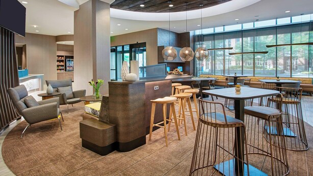 A modern interior with a central bar area, seating arrangements, and large windows offering natural light. - SpringHill Suites by Marriott Milwaukee Downtown (Milwaukee)