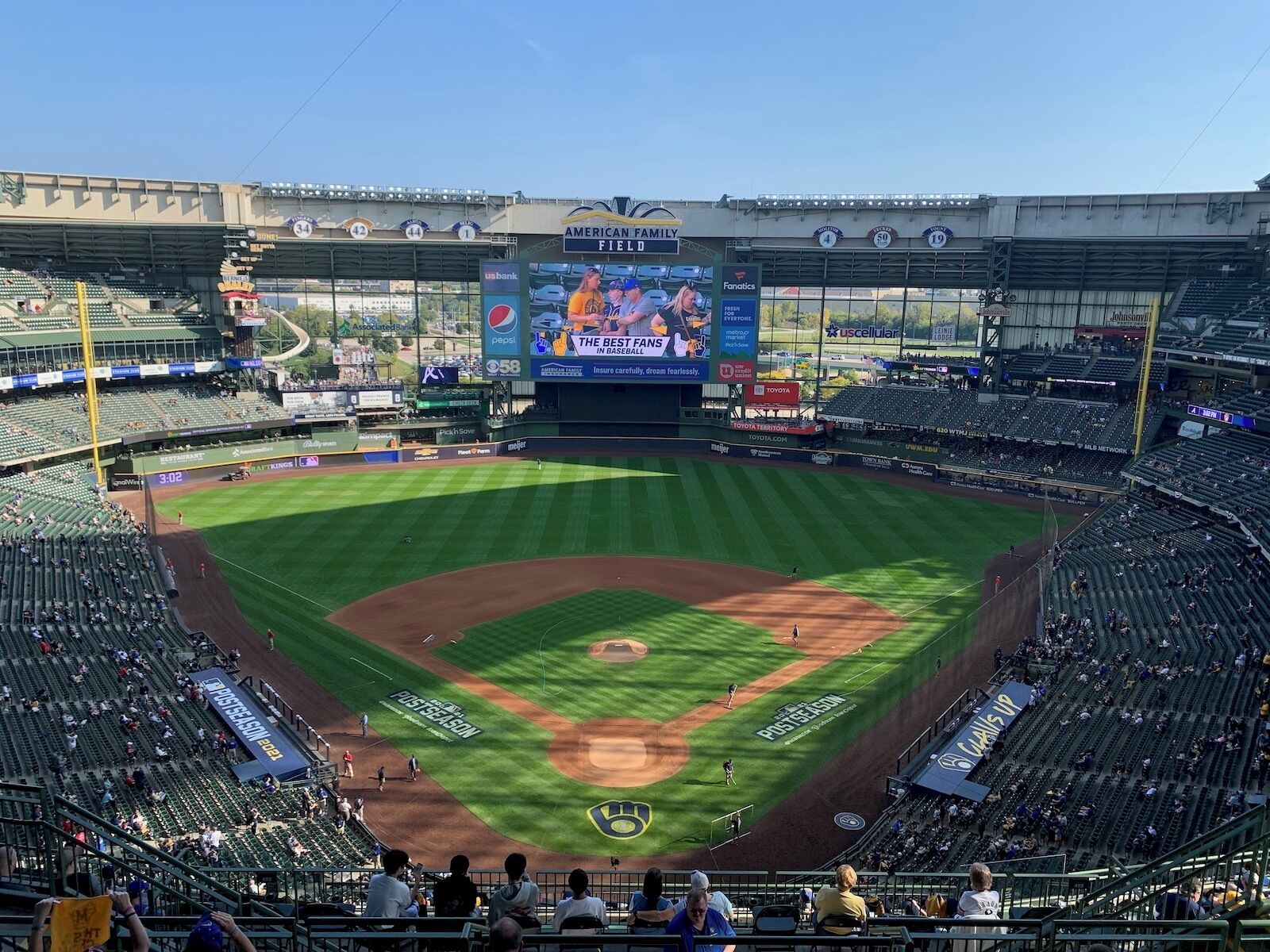 A baseball stadium with multiple levels of seating, a large scoreboard, and various advertisements.