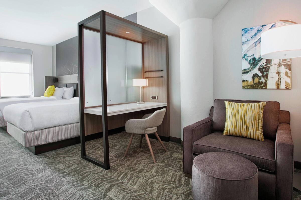 A hotel room with a bed, a desk, a chair, and a couch.