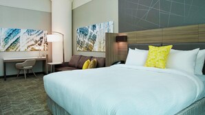 A hotel room with a large bed, a desk, a chair, and two wall-mounted artworks. - SpringHill Suites by Marriott Milwaukee Downtown (Milwaukee)