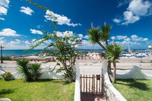A coastal view with a white gate, palm trees, and a clear blue sky. - B&B Sa Cruxitta (Portoscuso)