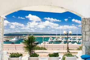 Un puerto deportivo con barcos, cielo azul despejado y un arco de piedra.