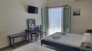 Habitación de hotel con cama, escritorio, silla, televisor y ventana con cortinas.