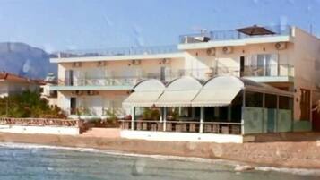 A coastal building with multiple balconies, a covered outdoor seating area, and a view of the sea.