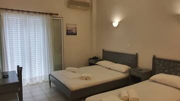 Une chambre d’hôtel avec deux lits, un bureau, une chaise, une fenêtre avec des rideaux et un luminaire fixé au mur.