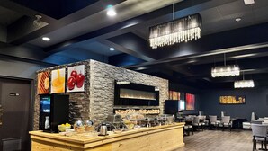 A breakfast bar with a stone wall backdrop, a digital clock, and various breakfast items.