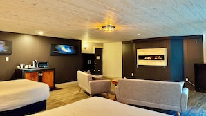 A hotel room with two beds, a sofa, a coffee station, a fireplace, and a TV. - Quality Inn Fort Frances (Fort Frances)